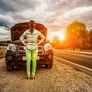 autopom extended car warranty woman in front of car by the side of the road open hood beautiful sunset in the background